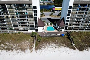A high-rise hotel with multiple balconies, a swimming pool, and a view of a body of water.