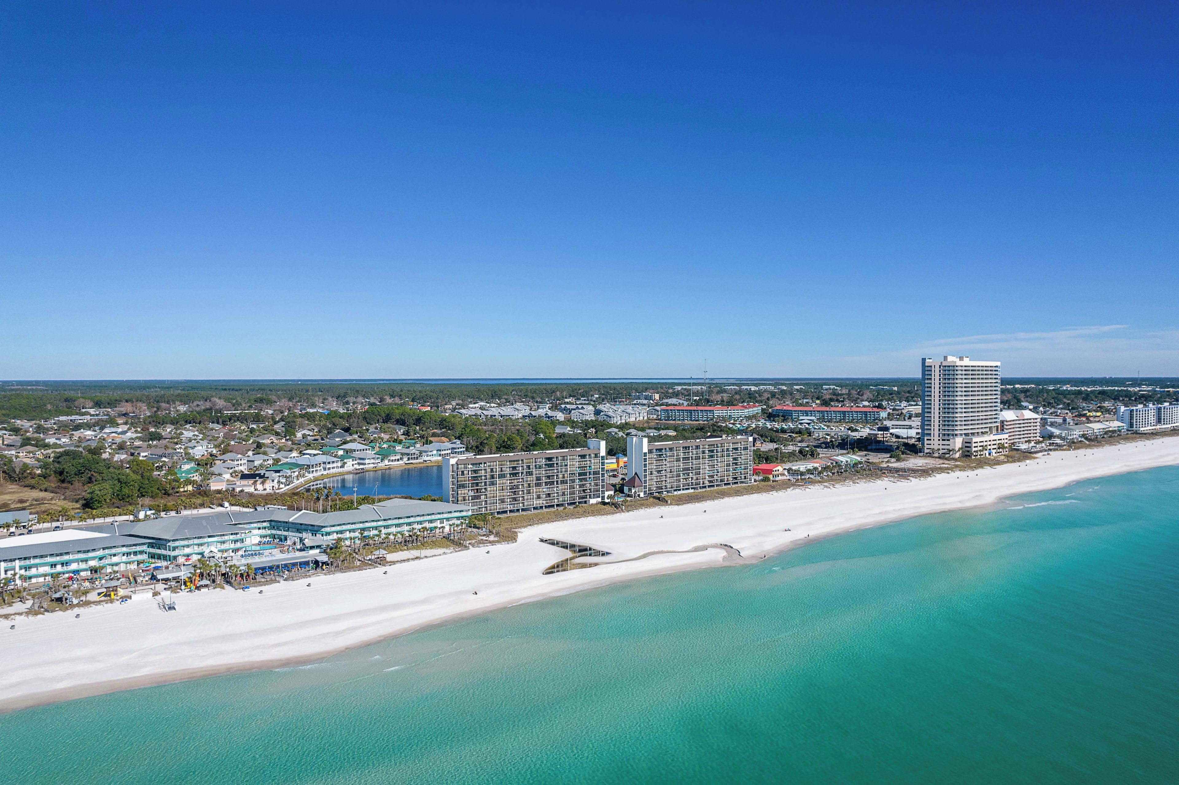 A coastal hotel with a beach view, multiple buildings, and a clear blue sky.