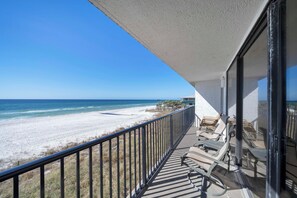 A balcony with a view of the beach and ocean.