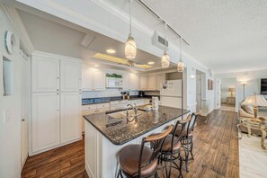 A kitchen with white cabinetry, a granite countertop, and a central island with bar stools.
