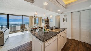 Una cocina moderna con una isla grande, un comedor con vistas y un balcón con vista al océano.