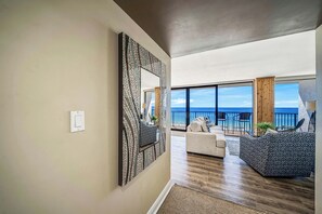 A modern living room with a large mirror, a sofa, and a view of the ocean.
