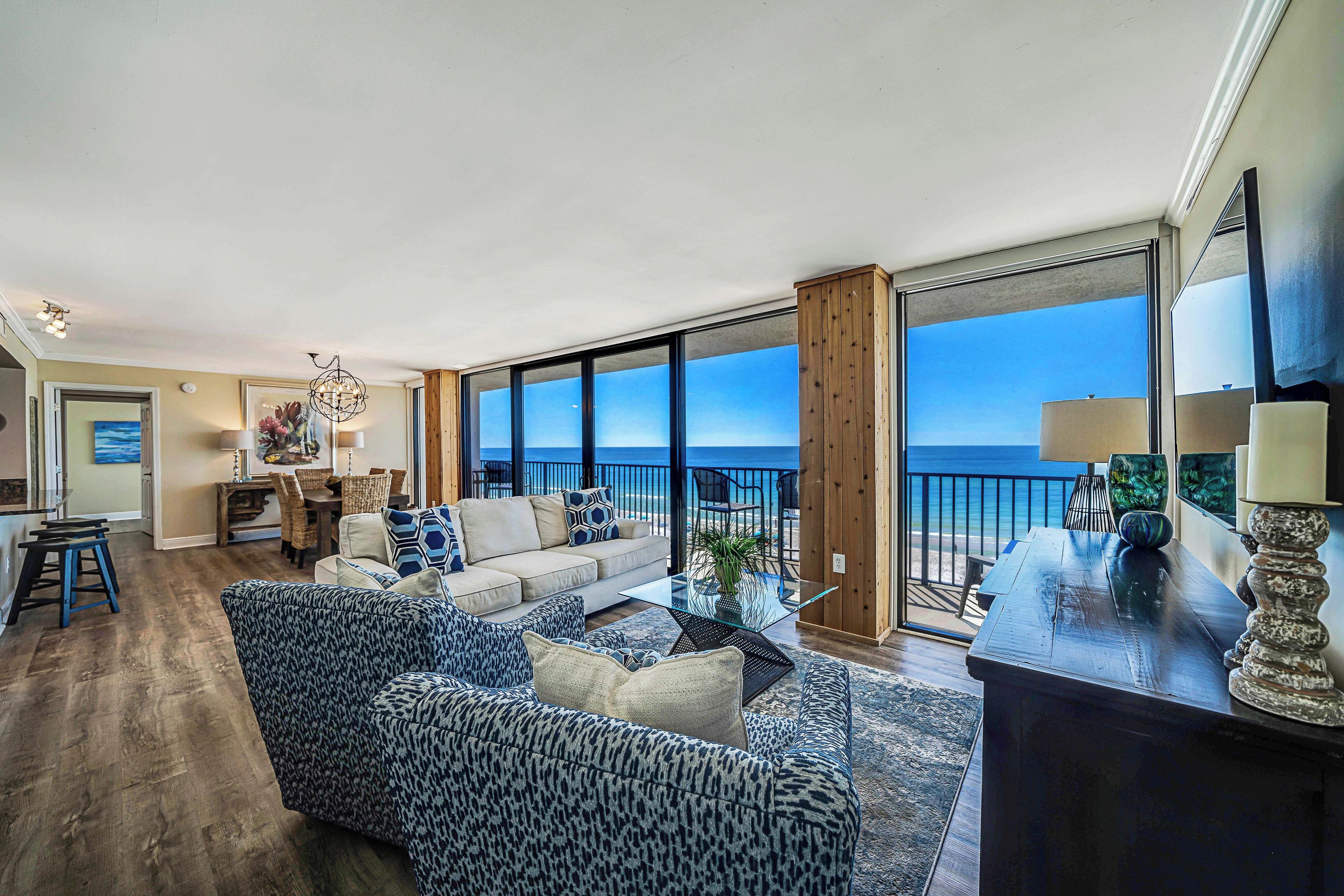 A spacious living room with a large sofa, a coffee table, and a view of the ocean through large windows.