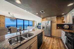 A modern kitchen with granite countertops, stainless steel appliances, and a view of the ocean.