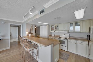 A spacious kitchen with a central island, white cabinetry, and a large window providing natural light.