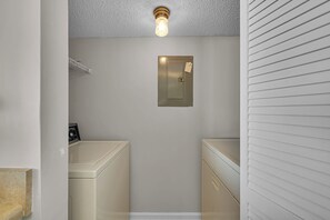 A laundry room with a washing machine, dryer, and a light fixture on the ceiling.