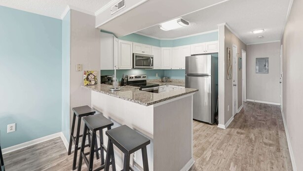 Cocina moderna con gabinetes blancos, electrodomésticos de acero inoxidable y encimera de granito.