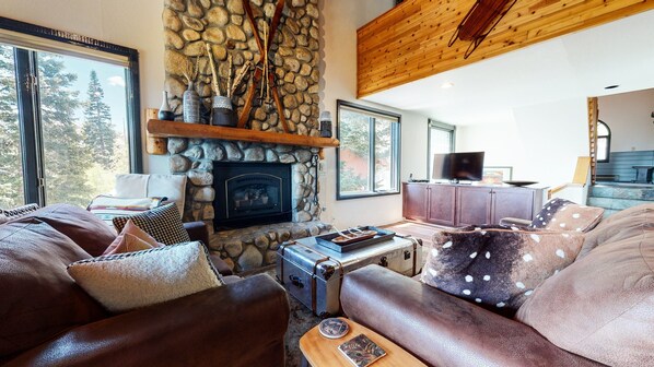 A cozy living room with a stone fireplace, leather sofas, and a television. - Bridges Townhome 5 Large, Remodeled Mountain View Townhome with Private Jacuzzi, Steps to Eagle Lodge by RedAwning (Mammoth Lakes)