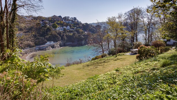 A coastal landscape with a grassy area, trees, and a view of houses on a hillside. - 4 BR (Sleeps 7) in Salcombe overlooking beach (Salcombe)