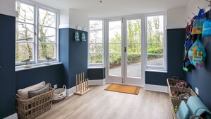 A room with large windows, a wicker basket, a dog bed, and a door leading outside. - 4 BR (Sleeps 7) in Salcombe overlooking beach (Salcombe)