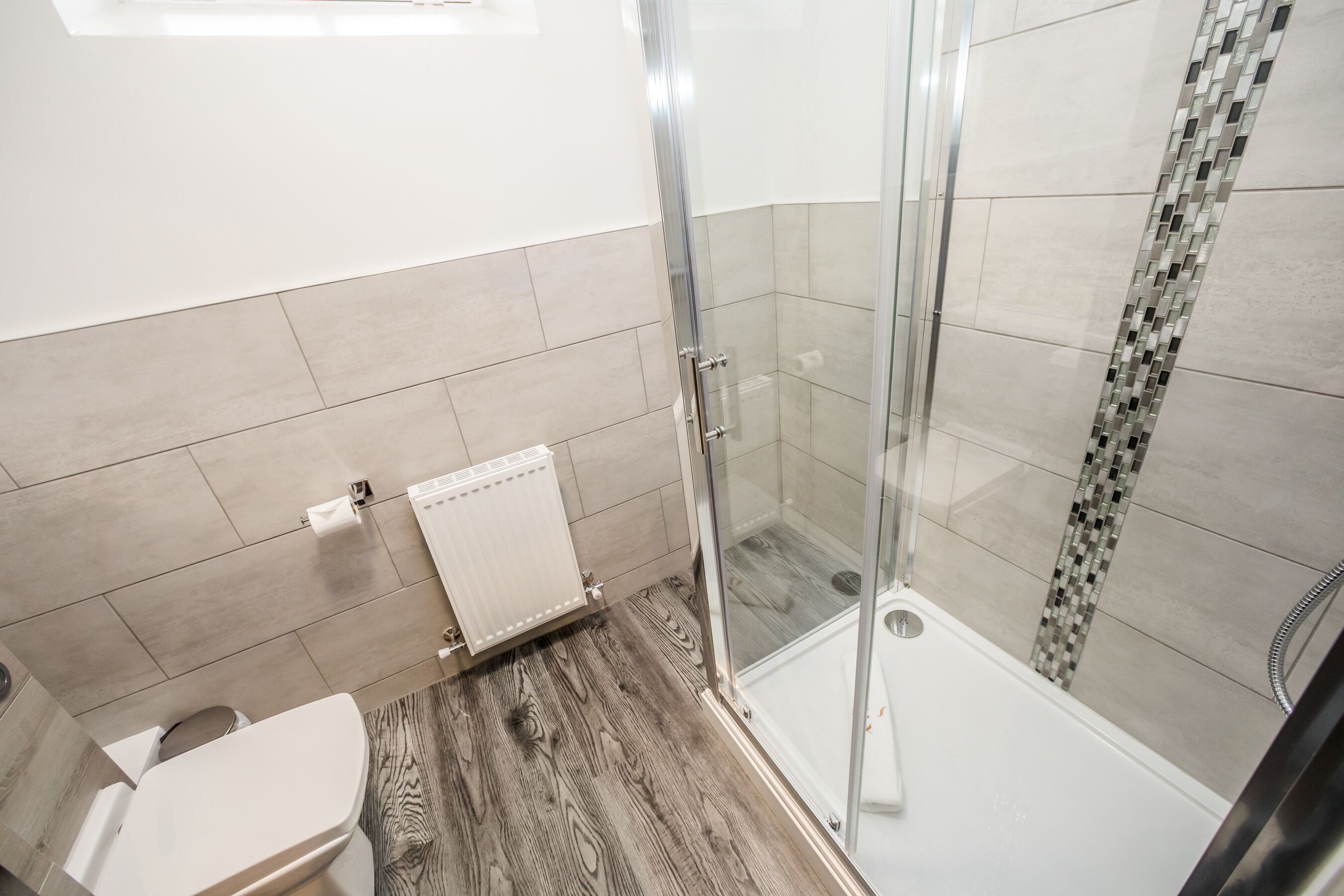 Une salle de bain moderne équipée d’une douche, de toilettes et d’un radiateur.