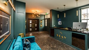 A hotel lobby with a reception desk, a blue sofa, and a modern chandelier. - Stay Hotel (Huddersfield)