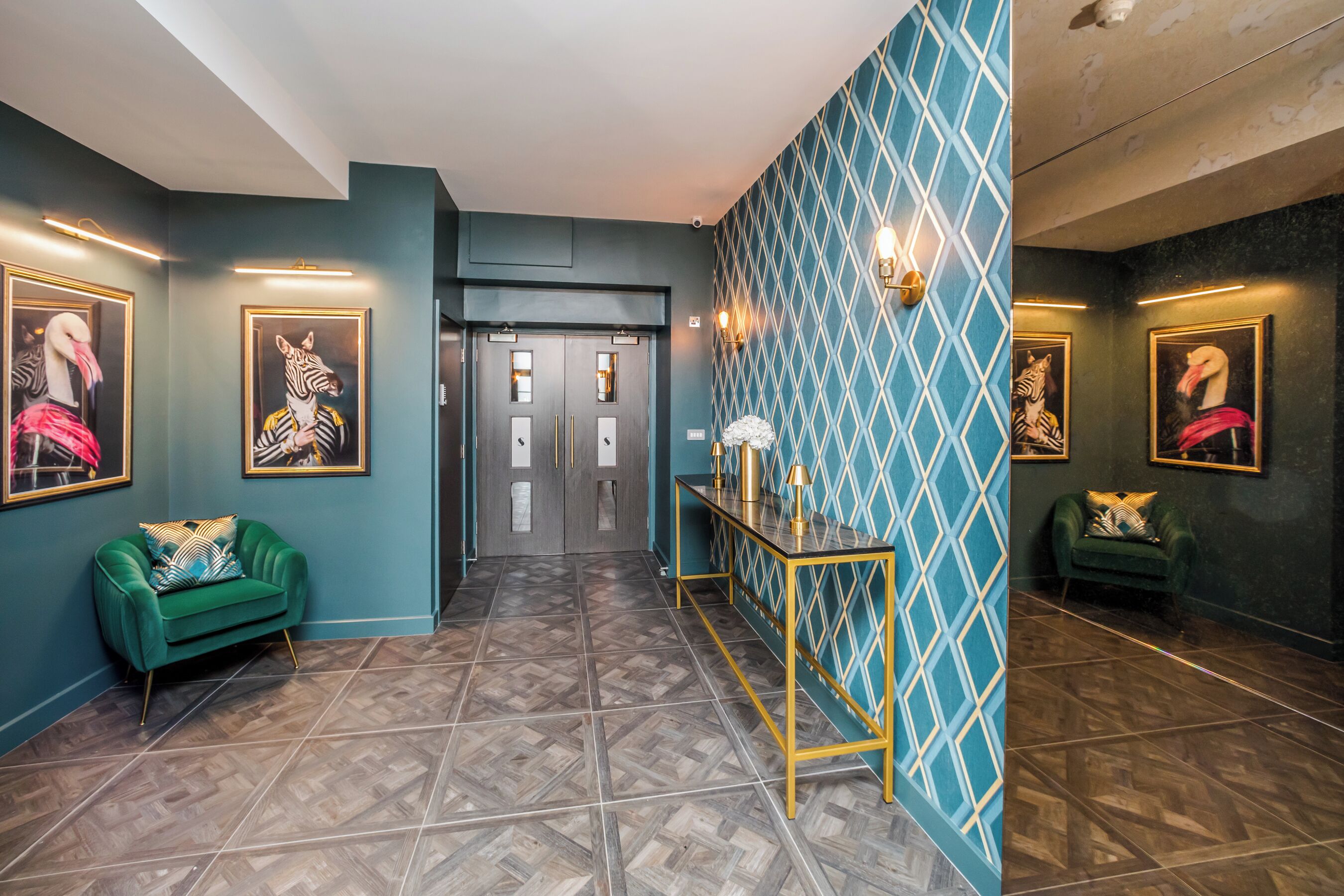 A hallway with patterned flooring, teal walls, and framed artwork.