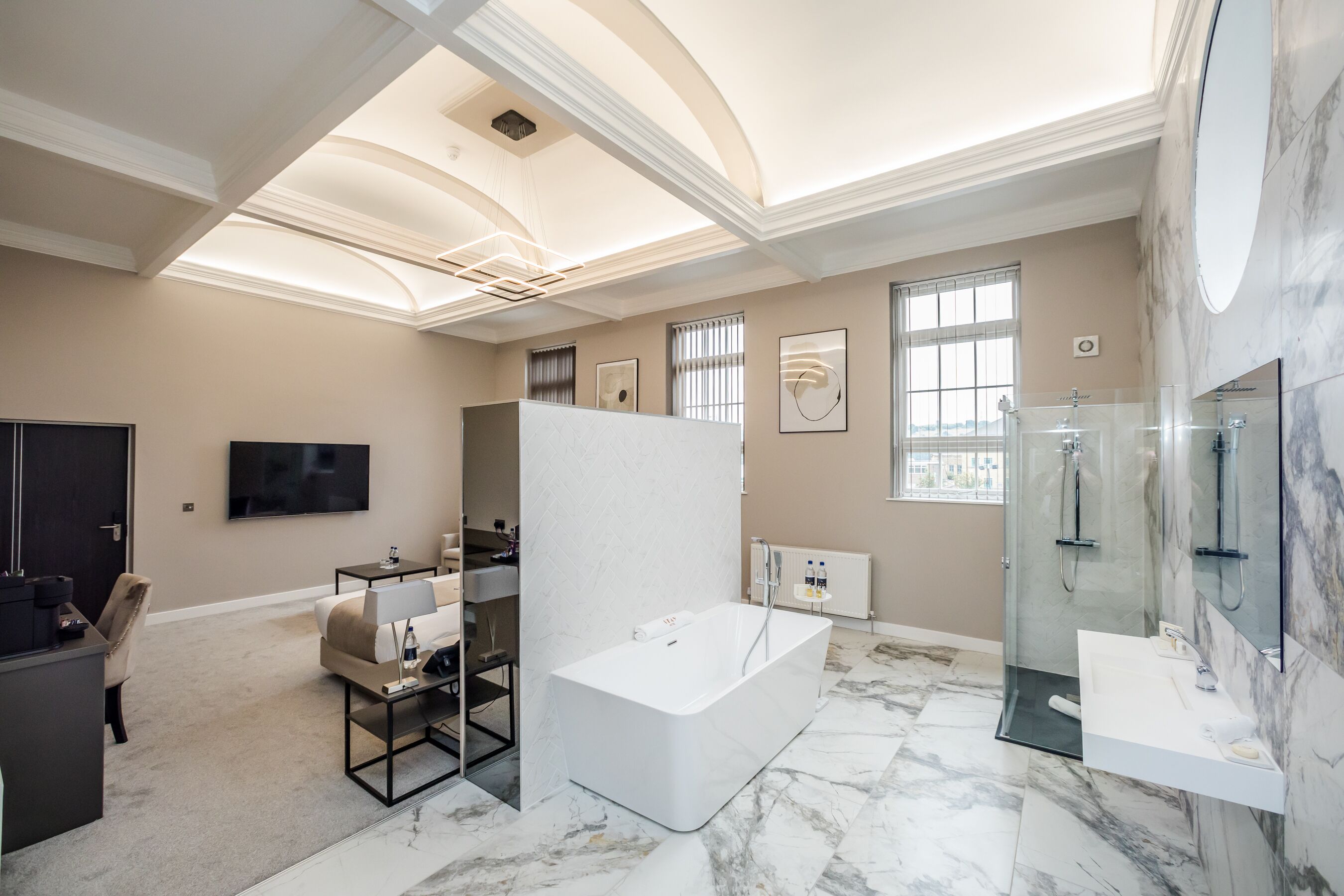 Une salle de bain moderne avec une baignoire sur pieds, une douche à parois de verre et un meuble-lavabo doté d’un grand miroir.