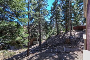 A forested area with a dirt path, a wooden deck, and a building with a porch. - Hidden Valley 37 Cozy Cabin with Great Complex Amenities Walk to the Village by RedAwning (Mammoth Lakes)
