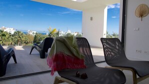 Ein Balkon mit Meerblick, zwei Stühle und ein Tisch mit Sonnenbrillen.