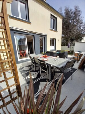 Un patio con una mesa de comedor, sillas y una parrilla.