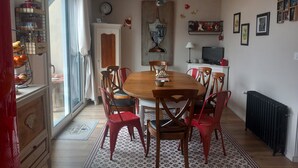Un comedor con mesa de madera y sillas rojas, un reloj en la pared y un radiador.