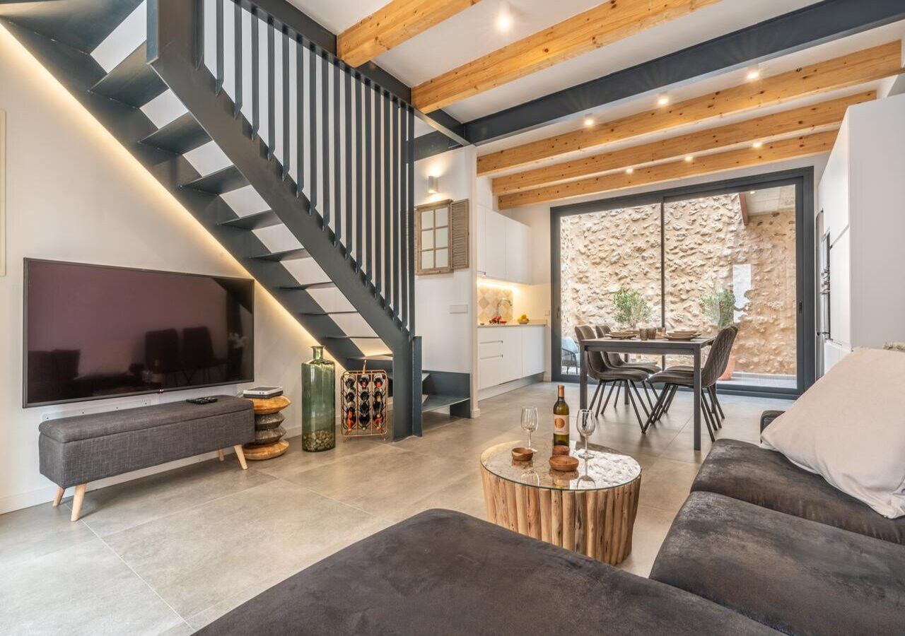 A modern living room with a staircase, a dining area, and a kitchen.