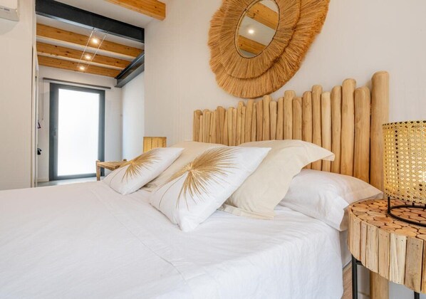 A bedroom with a bed, wooden headboard, and a round mirror.