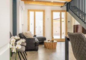 A modern living room with a sofa, a round wooden coffee table, and a staircase with a metal railing.
