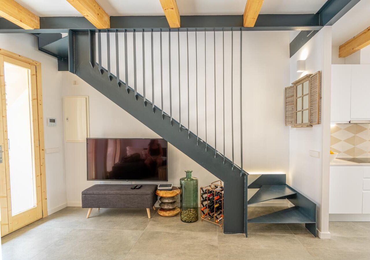 Un intérieur moderne avec un escalier, un téléviseur à écran plat, une console et un meuble à bouteilles.