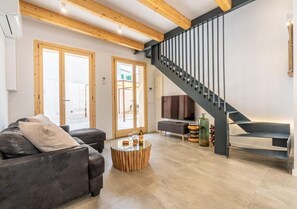 A modern living room with a sofa, a coffee table, and a staircase.