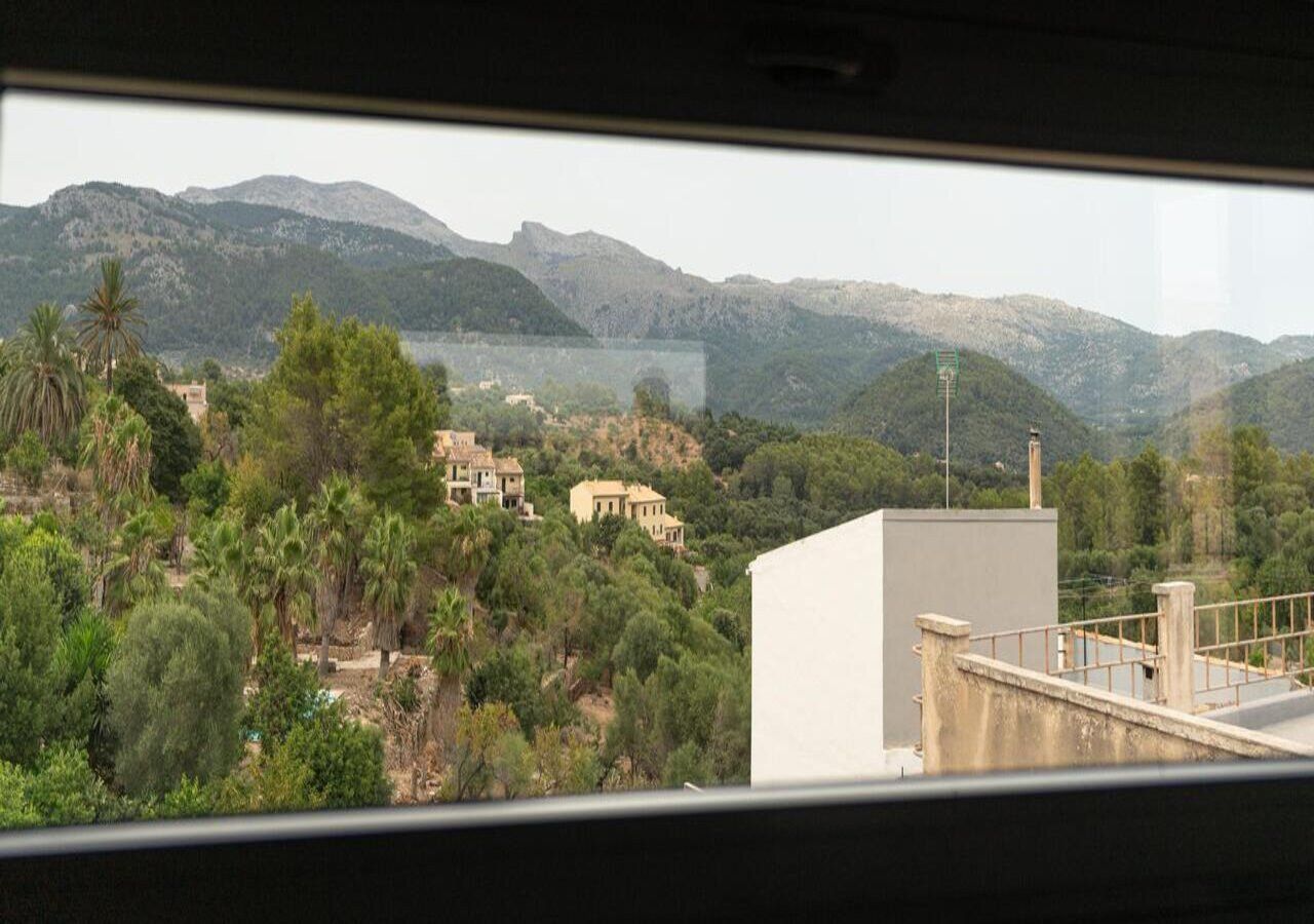 A view from inside a vehicle, overlooking a coastal area with buildings and mountains.