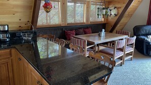 Una cucina accogliente con piano di lavoro in granito nero, mobili in legno e zona pranzo con sedie a righe e tavolo in legno.
