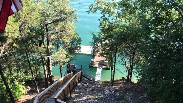 Un pontile di legno che conduce a un molo su un corso d'acqua, circondato da alberi.