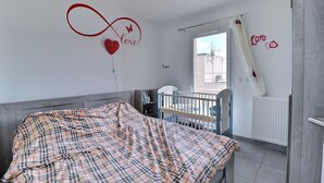 A bedroom with a bed, a crib, and a window with a view. - Villa en Location Près des Plages (Saint-Brès)