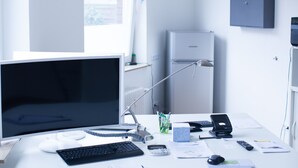 Een modern bureau met een computer, toetsenbord, muis en diverse kantoorbenodigdheden.