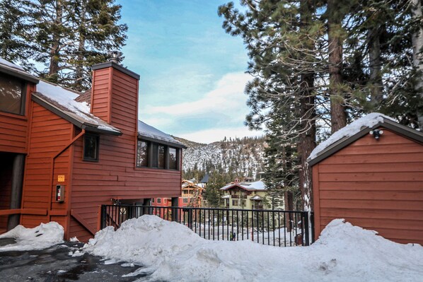 A red building with a snow-covered roof and a black metal fence in front. - Helios North 5, Convenient Location Across from Village, Underground Parking by RedAwning (Mammoth Lakes)