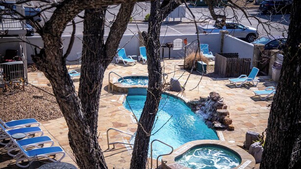 A pool area with lounge chairs, a hot tub, and a small waterfall feature. - River Access | Shared Pool & Spa | Close to Town! (New Braunfels)