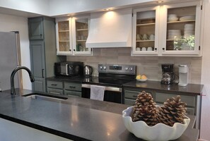A modern kitchen with grey cabinets, a stainless steel sink, a black microwave, a kettle, and a coffee maker. - Bright and cozy end unit condo in quiet complex. Close to North Star and beach (Kings Beach)