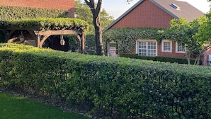 A brick house with a covered porch and a well-maintained hedge. - House in Westlake (Austin)