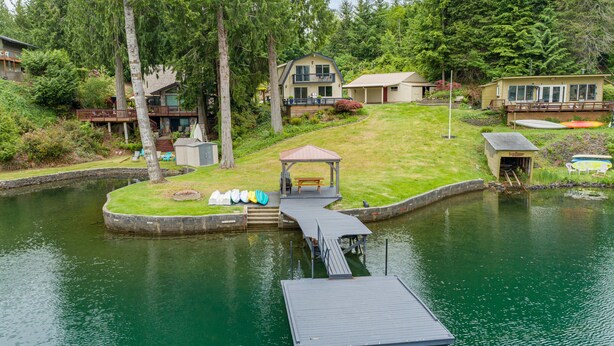 A lakeside property with a dock, a gazebo, and a small boat house.