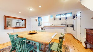 A kitchen with white cabinets, a wooden table, and green chairs.