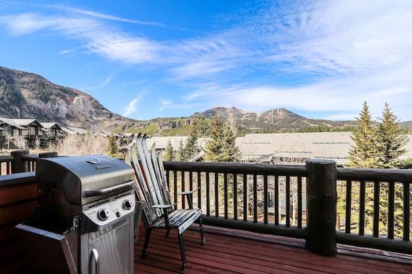 Une terrasse avec un barbecue et une chaise, offrant une vue sur un paysage montagneux.