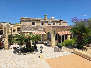 A traditional stone building with a tiled roof, outdoor seating area, and potted plants. - Casa Tranquilo. Charming Character House, Large Private Pool, Gardens, Moraira (Moraira)