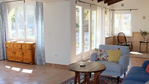 Un salón espacioso con un aparador de madera, un sofá azul con un cojín floral y una pequeña mesa redonda.