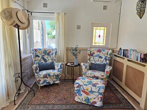 A room with two patterned armchairs, a small table with a vase, a radiator, and a bookshelf with books. - Casa Tranquilo. Charming Character House, Large Private Pool, Gardens, Moraira (Moraira)