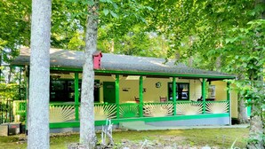 A green-roofed building with a covered porch, surrounded by trees and a stone pathway. - Cabin Near Dale Hollow Lake (Byrdstown)