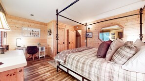 Cozy bedroom with a four-poster bed, desk, and ceiling fan.