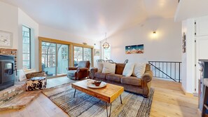Relax in this stylish living room with a large sofa, coffee table, and fireplace, plus a staircase leading to an upper level.