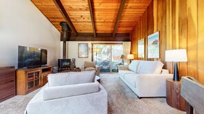 Una sala de estar acogedora con techo de madera, un televisor, una chimenea y dos sofás.