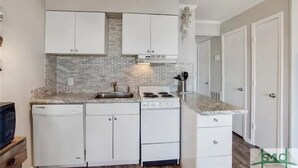 A modern kitchen with white cabinetry, a granite countertop, a dishwasher, and a stove. - Tybee Beach views, just steps to the ocean (Tybee Island)