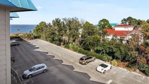 A parking area with three cars, a building with a red roof, and a view of the sea. - Tybee Beach views, just steps to the ocean (Tybee Island)