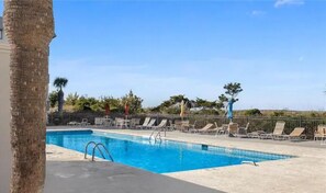 Relax by the serene pool surrounded by lounge chairs and a palm tree.