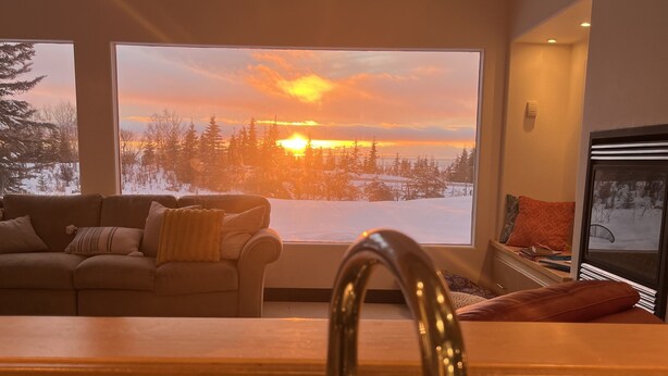 A kitchen with a large window overlooking a snowy landscape and a sunset. - Gorgeous Modern Alaskan Home with Ocean /Mt View 10 minute walk to sandy beach (Kenai)
